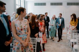 Guests smiling at wedding ceremony in bright room.
