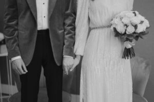 Bride and groom holding hands, wedding bouquet visible.