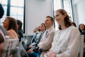 People sitting and smiling at an indoor event.