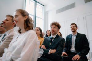 People smiling and listening during an event.