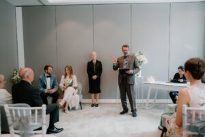 Wedding ceremony with seated guests and speaker.