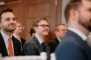 Smiling people in suits at an event.