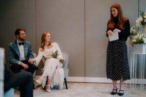 Couple sitting, woman giving wedding speech.