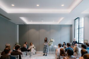 Wedding ceremony with seated guests and a speaker.
