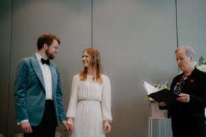 Couple getting married, holding hands, officiant reading