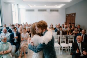 Couple hugging at wedding with guests applauding