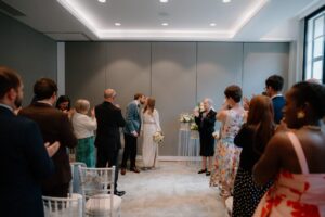 Newlyweds kiss in wedding ceremony with guests clapping.