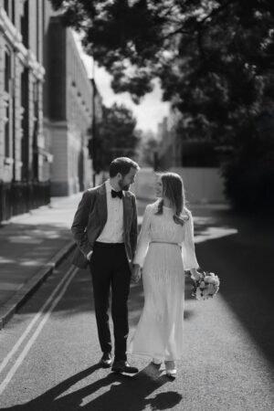 Couple walking down street in wedding attire.
