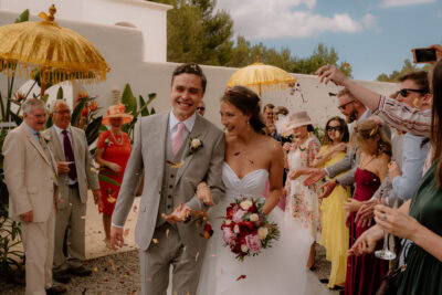Smiling couple at outdoor wedding ceremony with guests.