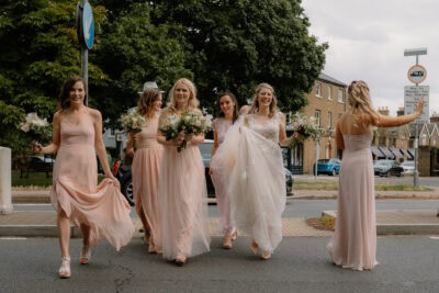 Bridesmaids and bride crossing street in wedding attire