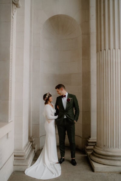 Bride and groom in elegant architectural setting.
