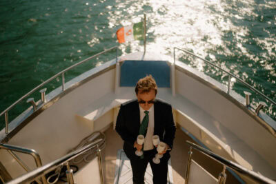 Person holding champagne glasses on a boat deck.