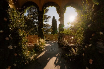 Sunlit garden terrace with flowers and chairs.
