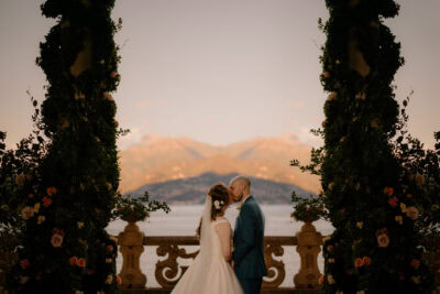 Bride and groom kissing by scenic lake view.