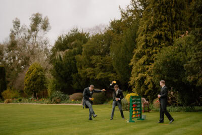 Men playing outdoor Connect Four game on grass.