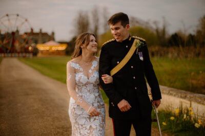 Bride and groom walking outside, amusement park behind.