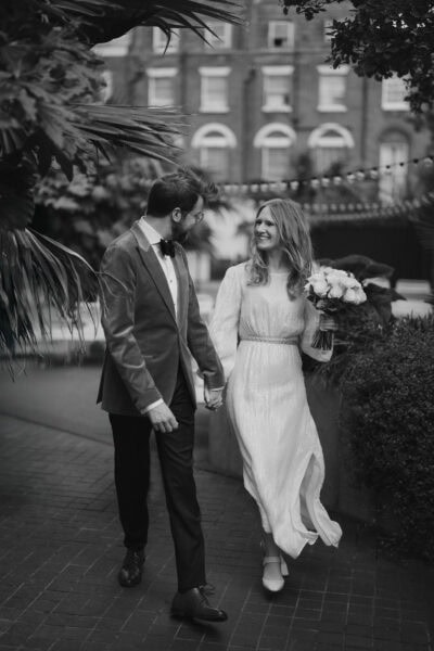 Happy couple walking on their wedding day, holding hands.