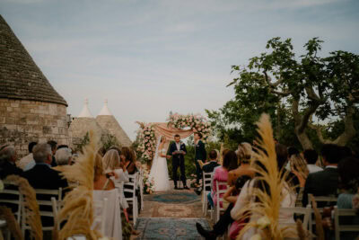 Outdoor wedding ceremony under floral archway.