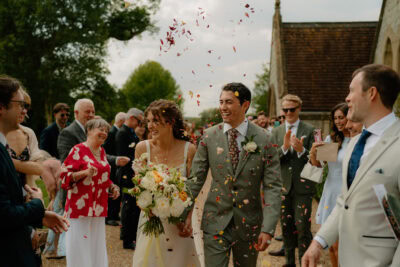 Bride and groom smiling with flower petals falling.
