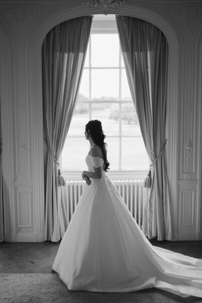 Bride in gown gazing outside window