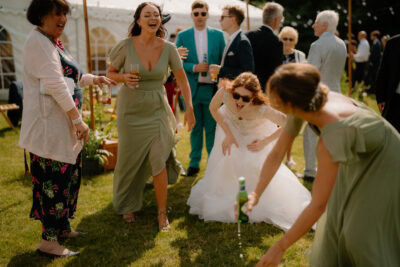 Wedding guests laughing and playing outside in garden.