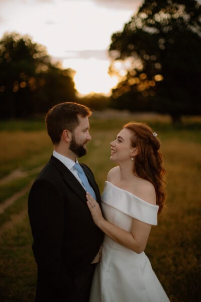 Couple smiling at sunset in a field.