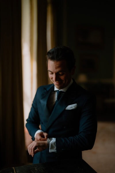 Man in formal suit adjusting watch