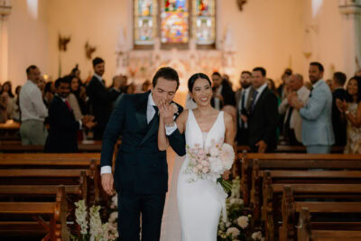 Wedding couple walking down church aisle, smiling.