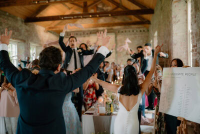 Guests celebrating at wedding reception with raised arms.