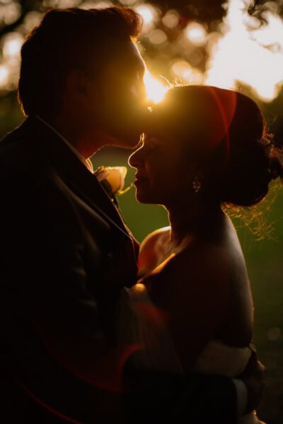 Couple embracing at sunset, creating romantic silhouette.
