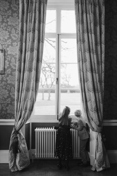 Two children looking out a large window.