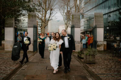 Smiling couple walks with wedding party in city scene.