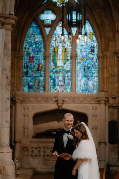 Bride and groom in church with stained glass window.