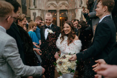 Happy couple exits church with confetti and smiles.