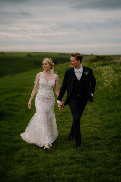 Couple holding hands in wedding attire outdoors.