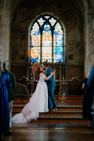 Couple kissing in church, stained glass background.
