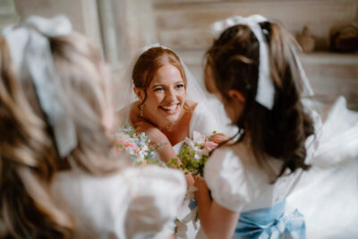 Bride smiling at bridesmaids with flowers.