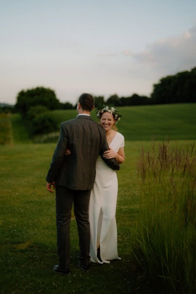Bride and groom laughing in countryside setting