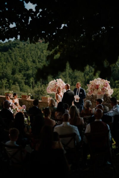 Outdoor wedding ceremony with guests and flowers.