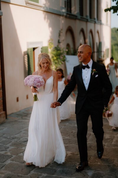 Bride and groom walking, holding hands joyfully.