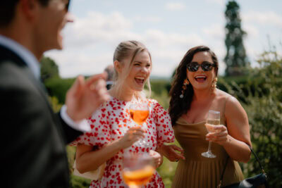 People laughing with drinks at outdoor event.