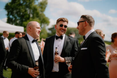 Men in suits laughing at outdoor gathering