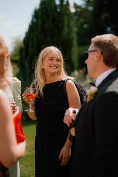 Smiling woman in black dress holding a drink.