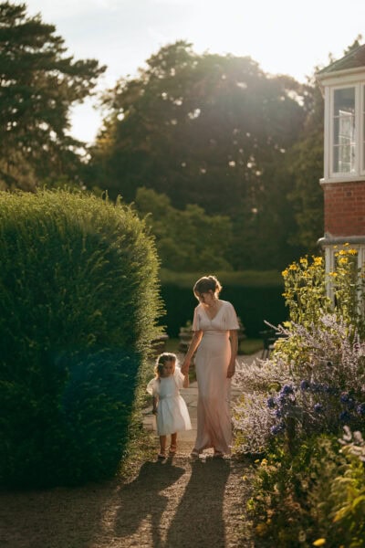 Woman and child walking in garden at sunset.