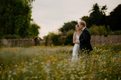 Couple embraces in flowery garden scene.