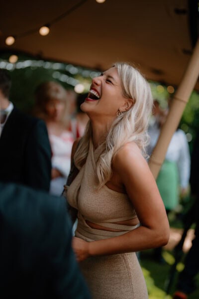 Woman laughing joyfully at outdoor event.