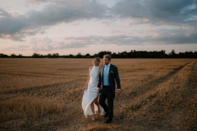 Couple walking in a field during sunset.