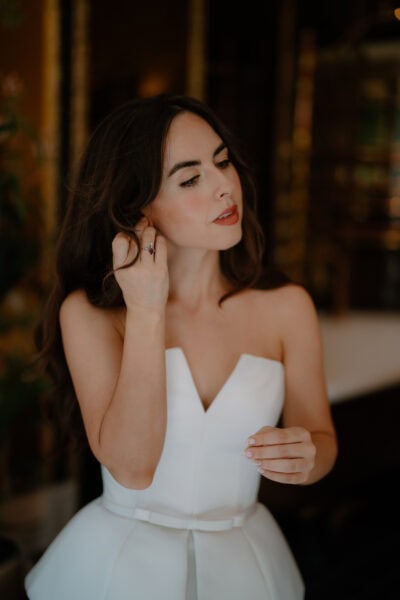 Woman in elegant white dress adjusting jewellery