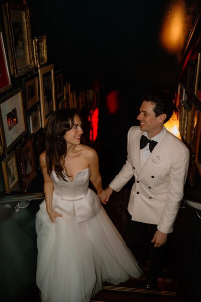 Couple smiling on staircase dressed formally.