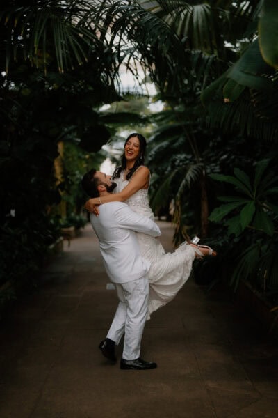 Bride and groom laughing in lush garden